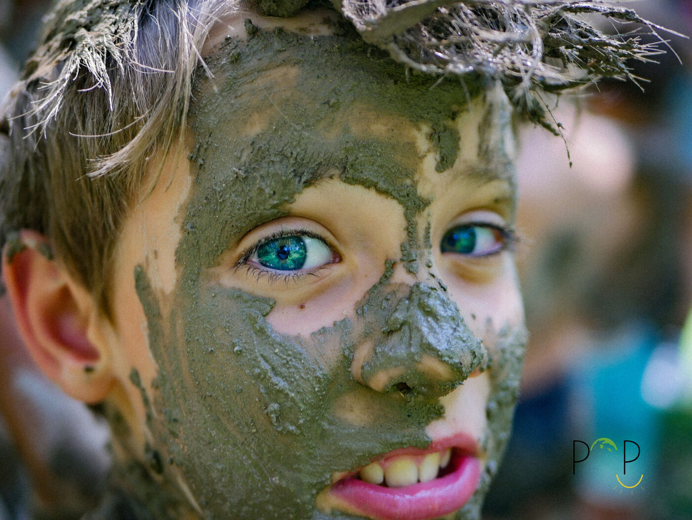 Un POPKid au visage couvert de boue, les yeux pétillants