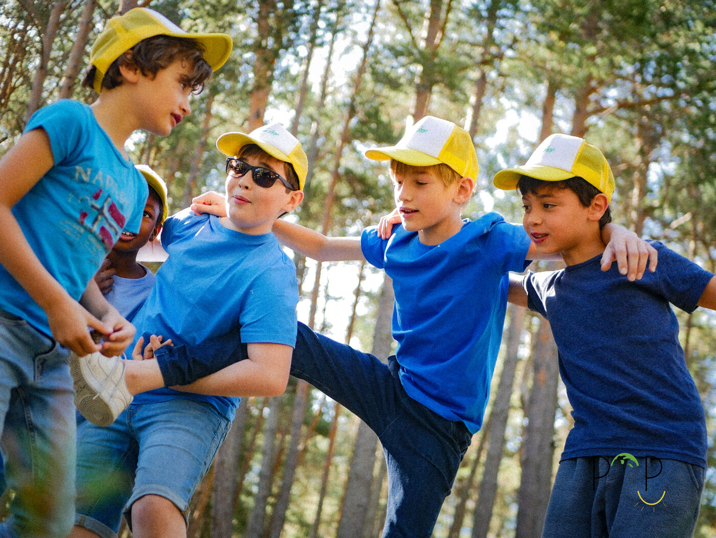 Des POPKids en casquette jaune jouent et rient dans la forêt